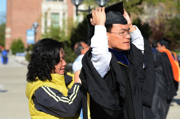 Pei Li Xia adjusts her son Yi Ren's hood outside of Rackham Auditorium for commencement on Friday morning. Melanie Maxwell I AnnArbor.com